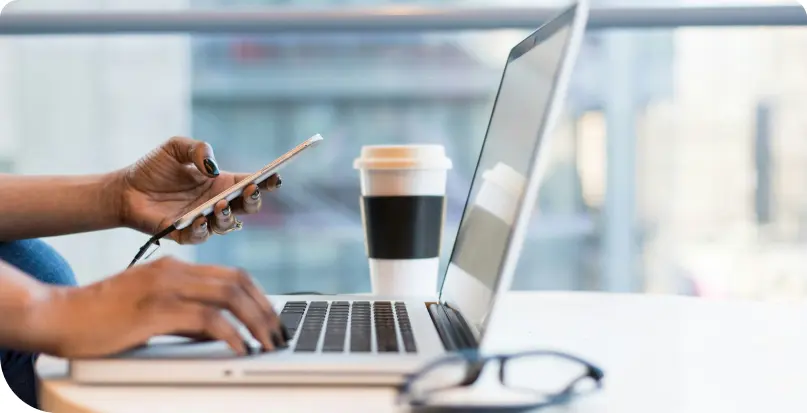 A person checking a phone while working on the computer 